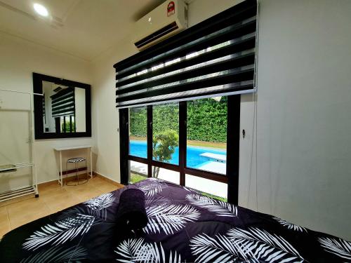 Kampong Alor GajahにあるPrivate 4Bedroom Villa Pool,BBQ,Karaoke, Afamosa Resortのベッドルーム1室(プールの景色を望む大きな窓付)