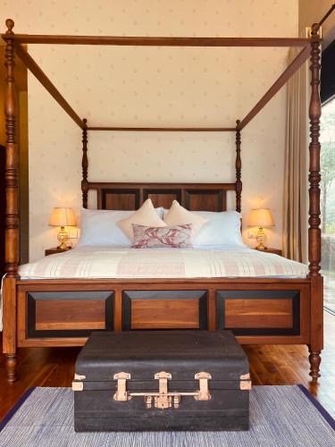 a canopy bed with a wooden frame with a trunk at Rosewood Manor in Botiyatenna