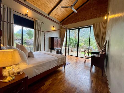 a bedroom with a bed and a desk and windows at Rosewood Manor in Botiyatenna