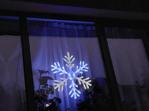 a snowflake is lit up in a window at FULG DE NEA in Sinaia