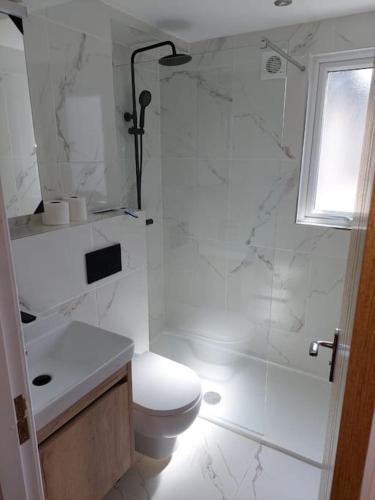 a white bathroom with a toilet and a shower at Jester Court - 2 bed apartment in the Centre of Windermere Village - FREE off-site Health Club access with Pool, Sauna, Steam Room & Gym in Windermere