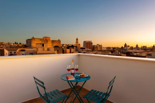 a table with two chairs and wine glasses on a balcony at Coeo Parras Design Apartments in Málaga