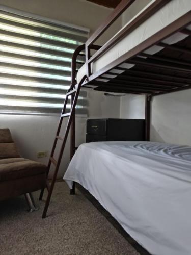 Casita Boquete في بوكيتي: غرفة نوم مع سرير بطابقين وكرسي