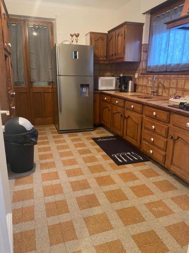 une cuisine avec un réfrigérateur en acier inoxydable et des armoires en bois dans l'établissement Maison 5 chambres 2 salons, à Saint Pierre en Faucigny