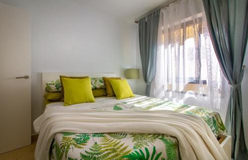 een slaapkamer met een bed met gele kussens en een raam bij Henry's Apartment Aguilas in Águilas
