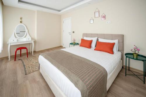 a bedroom with a large bed with orange pillows and a mirror at ABC Apart Hotel in Antalya