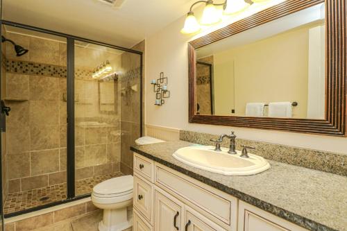 Un baño con lavabo, inodoro y espejo. en Sand Dollar 2-201, en St. Augustine