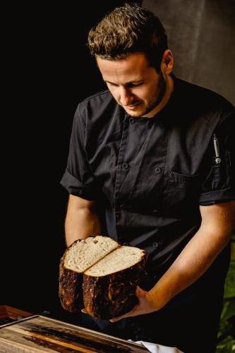 a man holding a loaf of bread on a table at Ta' Tereza In Manwel Dimech in Sliema