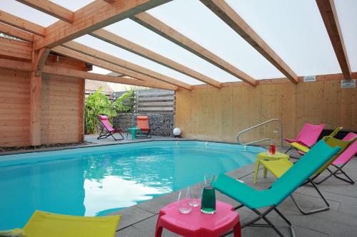 a swimming pool with chairs and a table next to it at Les Portes de la Vallee in Turckheim