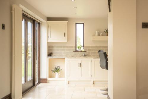 a kitchen with white cabinets and a window at Tockwith Lodge Barn in York