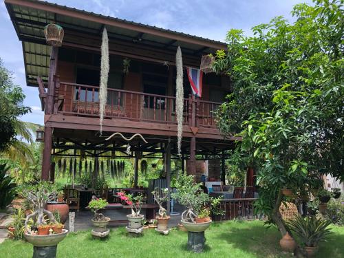 a house with a balcony with potted plants in the yard at Metha Country View Homestay Singburi in Ban Kho Sai