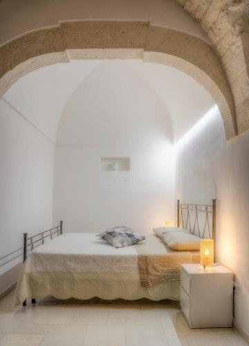 a bedroom with a bed in a white room at Home Pedra in Ceglie Messapica