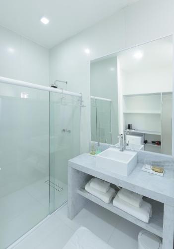 a white bathroom with a sink and a shower at Pe na Areia Boutique Hotel in Japaratinga