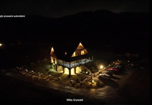 a large house with lights on it at night at Willa Grywałd in Grywałd