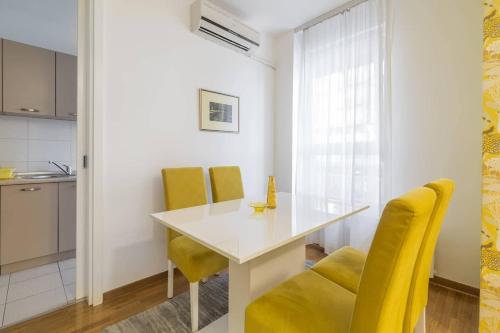 a dining room with a white table and yellow chairs at Delta Residence Belville in Belgrade