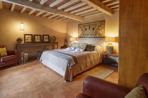 een slaapkamer met een bed, een bank en een stoel bij Villa Bobolino in Cortona