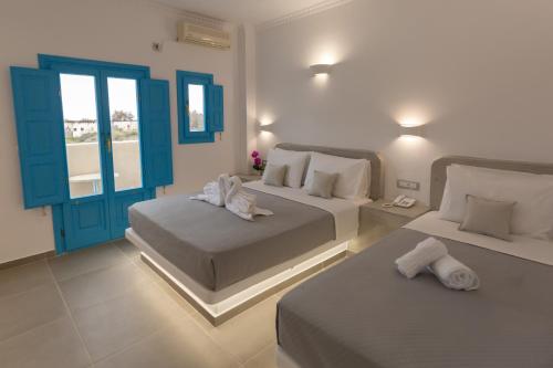 2 Betten in einem Zimmer mit blauen Türen und weißen Wänden in der Unterkunft Perissa Bay in Perissa