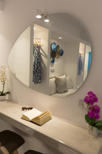 a mirror above a table with a book and flowers at Perissa Bay in Perissa