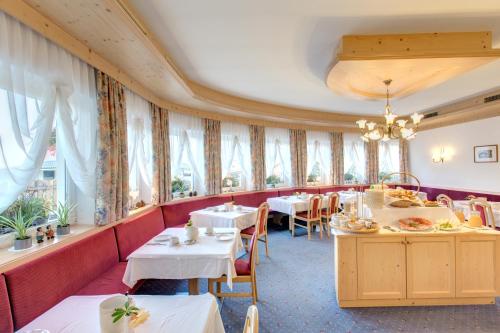ein Restaurant mit Tischen, Stühlen und Fenstern in der Unterkunft Hotel Piccolo in Obereggen