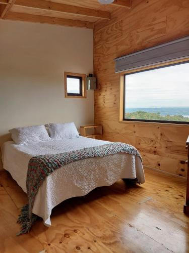 a bedroom with a bed and a large window at Casa Puente de Chiloé in Castro
