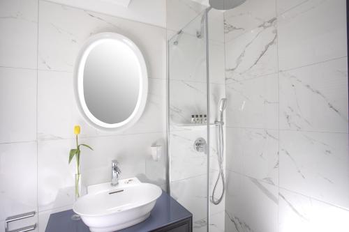 Baño blanco con lavabo y espejo en ARTIST Boutique Hotel en Viena