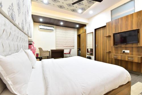 Schlafzimmer mit einem weißen Bett und einem Flachbild-TV in der Unterkunft Hotel Signature Prime Vaishali Nagar Jaipur in Jaipur