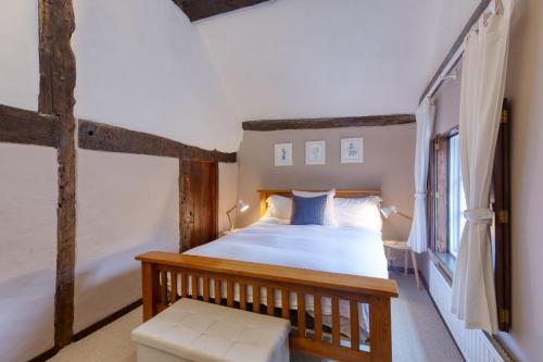 een slaapkamer met een houten bed en een raam bij White Cross Cottage in Woodbury