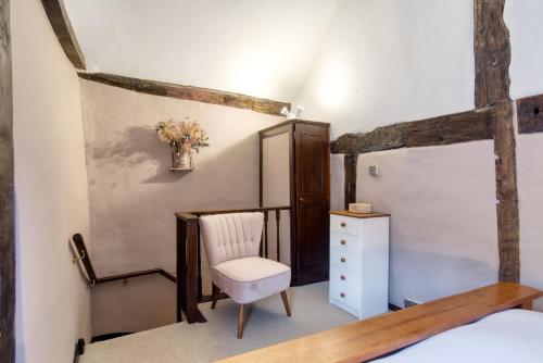 1 dormitorio con cama, silla y vestidor en White Cross Cottage, en Woodbury