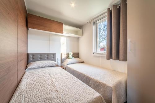 2 Betten in einem kleinen Zimmer mit Fenster in der Unterkunft Centro Vacanze - Garden River in Altidona