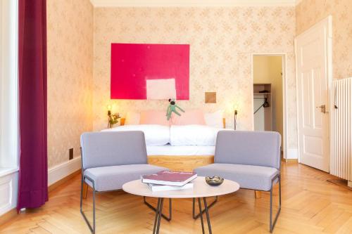a bedroom with a bed and two chairs and a table at Hotel Beau Séjour Lucerne in Luzern