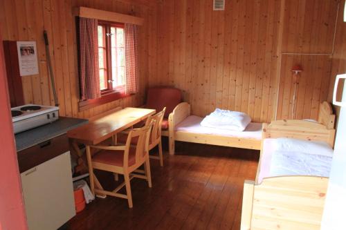 ViksdalenにあるHov Hyttegrendのテーブル、ベッド、キッチンが備わる小さな客室です。