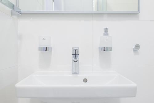 a white bathroom sink with a chrome faucet at Salón MISSEN in Omšenie