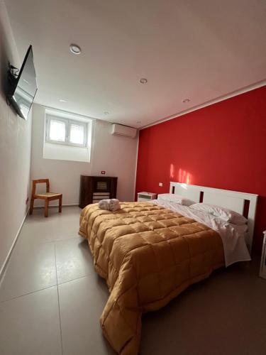 een slaapkamer met een groot bed met een rode muur bij B&B VILLA LA GINESTRA in Boscoreale