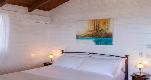 a white bedroom with a bed with two lamps at Vissala Village in Chort&aacute;ta