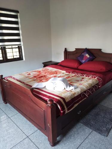 a bedroom with a bed with red sheets and red pillows at Cherry blossom homestays Munnar 2BHK in Munnar