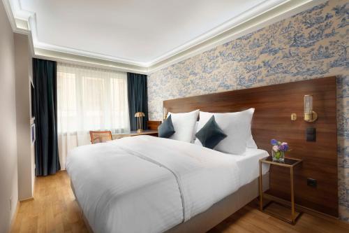 a bedroom with a large white bed and blue wallpaper at ARTIST Boutique Hotel in Vienna