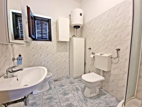 uma casa de banho branca com um lavatório e um WC em Apartman Irena with terase end private parking em Okrug Donji
