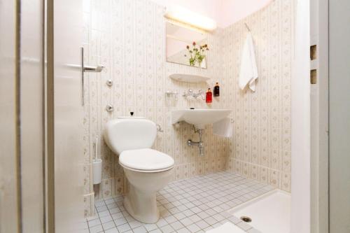 a white bathroom with a toilet and a sink at Hotel Beau Séjour Lucerne in Luzern