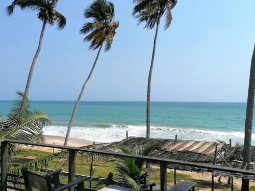 uitzicht op het strand vanaf het balkon van een resort bij Afro Beach Eco Resort Butre in Butre