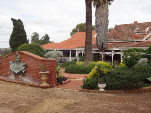 a house with a palm tree and a brick wall at Hillside Country Retreat in York