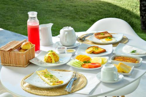 Biały stół z talerzami żywności w obiekcie Pe na Areia Boutique Hotel w mieście Japaratinga