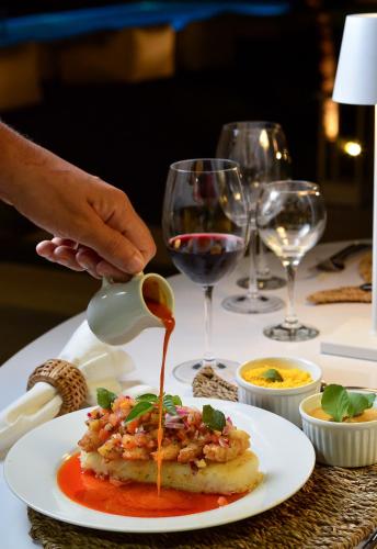 a person pouring sauce onto a plate of food on a table at Pe na Areia Boutique Hotel in Japaratinga