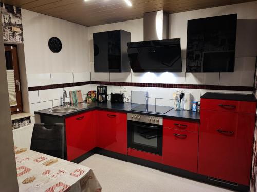 een keuken met rode kasten en een zwarte kachel bij Apartment "Zur Rotbuche" in Lindau