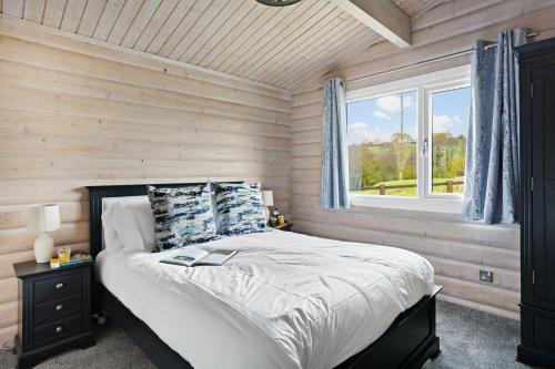 a bedroom with a bed in a wooden wall at Chestnut, 6 Fingle Glen Lodges in Holcombe Burnell