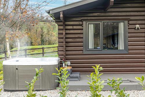 a bath tub sitting on a deck next to a cabin at Chestnut, 6 Fingle Glen Lodges in Holcombe Burnell