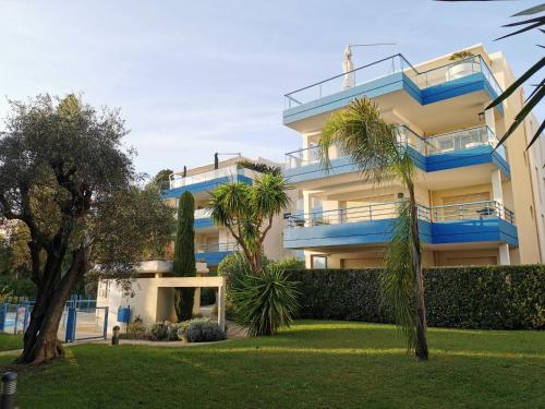 カンヌにあるResidence Paradis Bleuの青いバルコニーとヤシの木があるアパートメントビル
