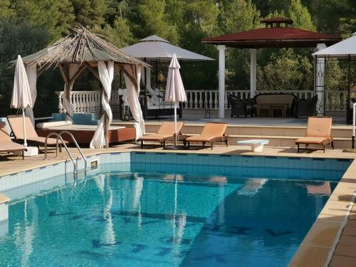 a swimming pool with chairs and a gazebo at Villa Askamnia and Suites in Nikiti