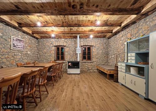 La Pietra Family Hotel في ميديوغوريه: غرفة طعام مع طاولات خشبية وجدران حجرية