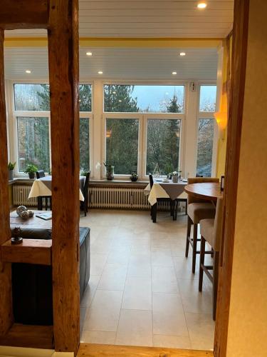een grote kamer met ramen, tafels en stoelen bij Haus am See in Bad Sachsa