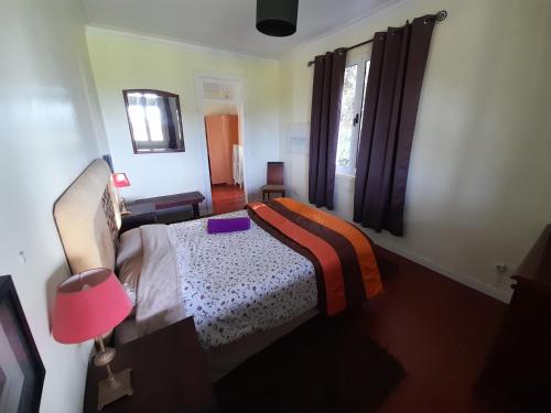 a bedroom with a bed and a lamp and a window at Casa da Mediana in Ribeira Grande